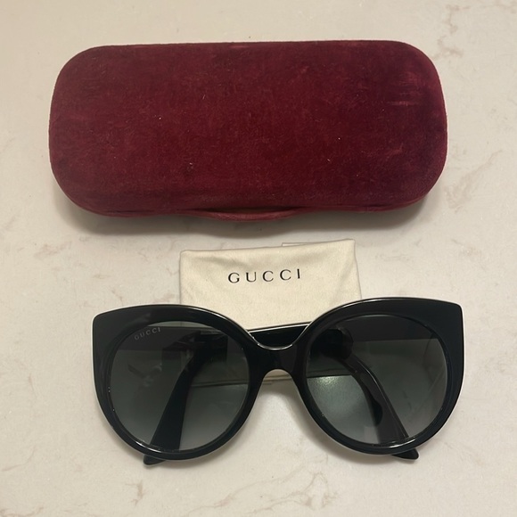 Gucci Cat Eye Black Sunglasses with golden logo temples and a logo on a lense